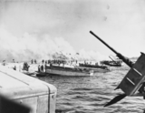 photo en noire et blanc de 1944 avec des bateaux militaires accostant sur la plage